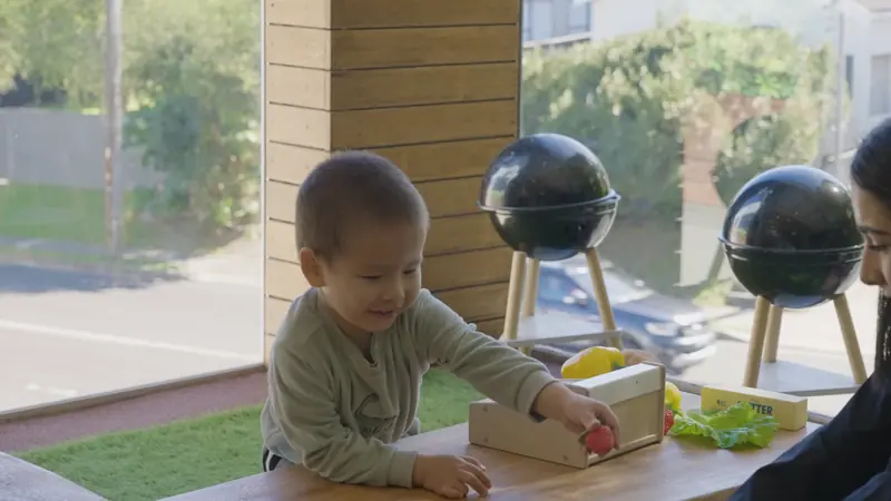 A child playing with a pretend kitchen by the window